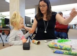 Librarian assists child with craft 