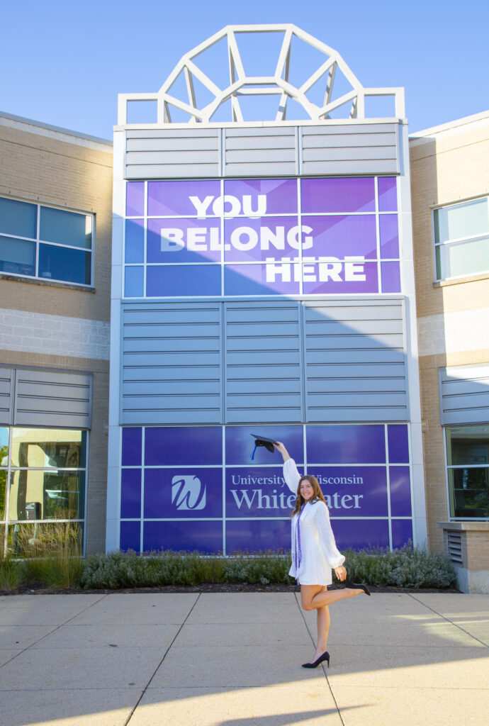 Student in front of the University Center "You Belong Here" sign.